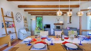 A dining area with a wooden table set for a meal, a television in the background, and a living room with a sofa and a fireplace. - Casa Felicit 8 in Ripe San Ginesio (Ripe San Ginesio)