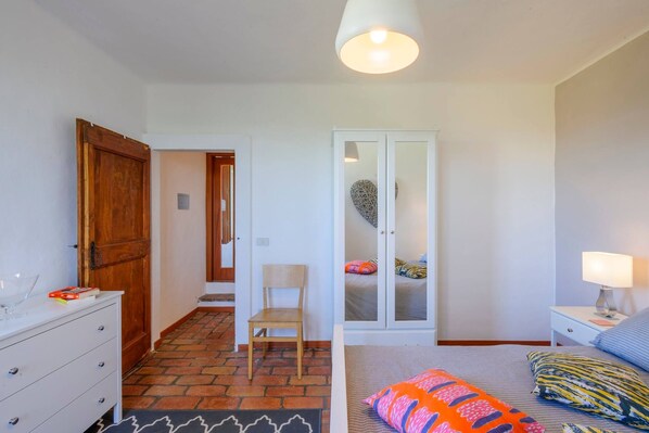 A bedroom with a bed, bedside table, lamp, chair, wardrobe, and a door. - Casa Felicit 8 in Ripe San Ginesio (Ripe San Ginesio)