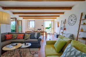 En rummelig opholdsstue med en sofa, en mindre sofa og et spisebord.