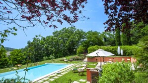 A swimming pool surrounded by a well-maintained garden with a patio area and outdoor seating. - Casale Belvedere 8 1 by Marche Holiday Villas (Pesaro)