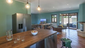 Una cucina moderna con un piano di lavoro in legno, un frigorifero e una zona pranzo con sedie e tavolo.