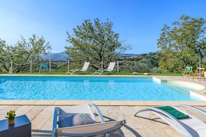 Ein Schwimmbecken mit Liegestühlen und Blick auf die Landschaft.