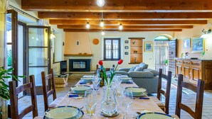 A dining area with a long table set for a meal, wooden beams on the ceiling, and a fireplace in the background. - Casale Partemio 8 in Cartoceto (Cartoceto)