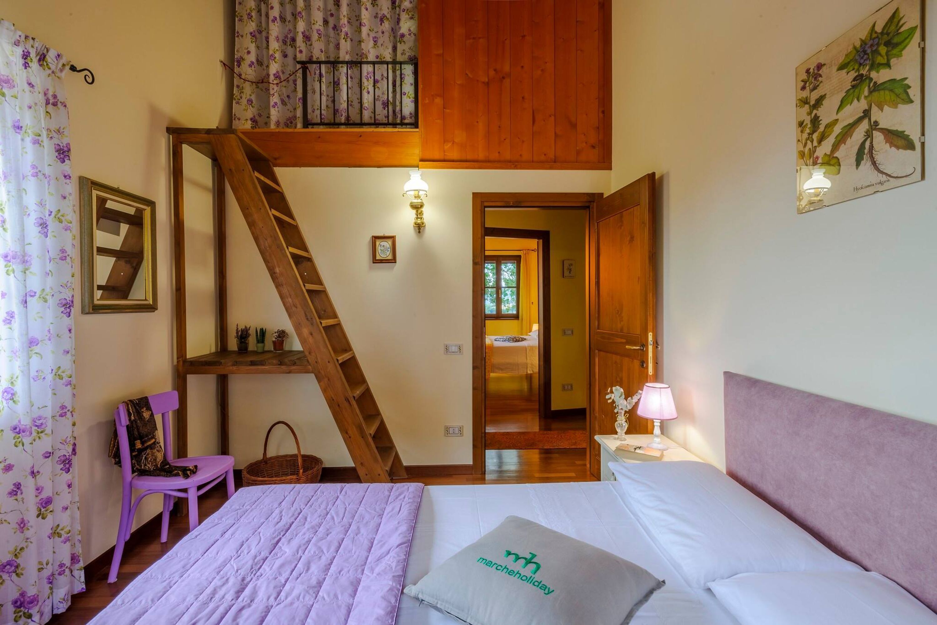 A bedroom with a bed, a wooden ladder, a chair, a nightstand, and a wall-mounted lamp.