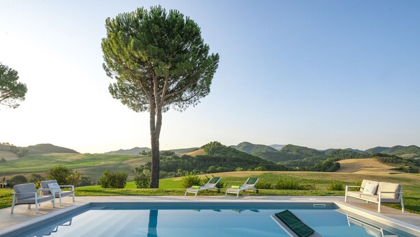 A swimming pool with lounge chairs and a view of rolling hills. - Villa Paola 10 by Marche Holiday Villas (Sant'Angelo in Vado)