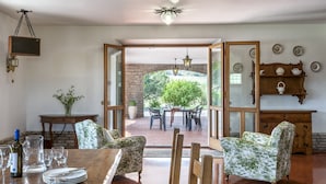 A dining area with a wooden table, chairs, and a view of an outdoor patio. - Villa Paola 10 by Marche Holiday Villas (Sant'Angelo in Vado)