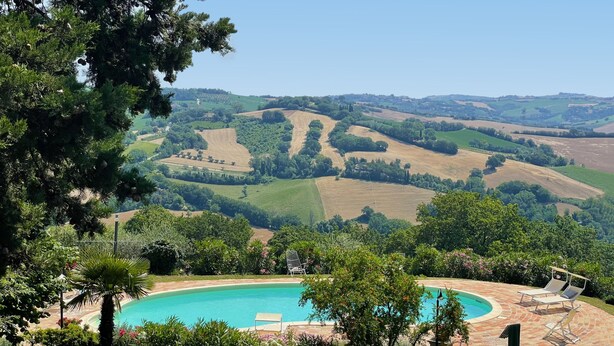 A pool surrounded by lush greenery and a view of rolling hills. - Casa Zefiro 4 in Orciano di Pesaro (Terre Roveresche)