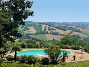 A pool surrounded by lush greenery and a view of rolling hills. - Casa Zefiro 4 in Orciano di Pesaro (Terre Roveresche)