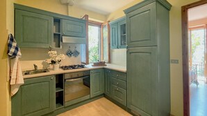 A kitchen with green cabinets, a stove, and a window. - Casa Zefiro 4 in Orciano di Pesaro (Terre Roveresche)