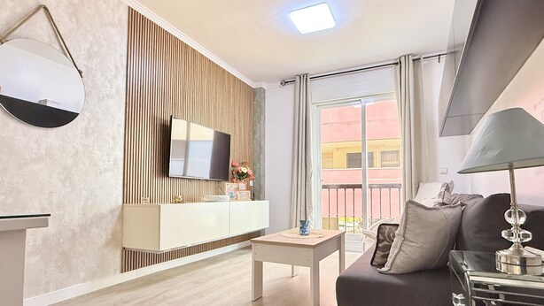 Ein modernes Wohnzimmer mit Flachbildfernseher, einer Couch, einem Couchtisch und einer Lampe.