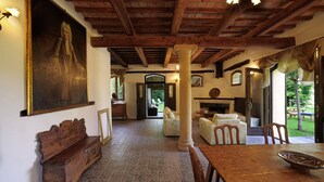 A spacious room with a wooden ceiling, a large painting on the wall, a bench, and a dining table with chairs. - Luce tra i Faggi 8 in Montemaggiore al Metauro (Colli al Metauro)
