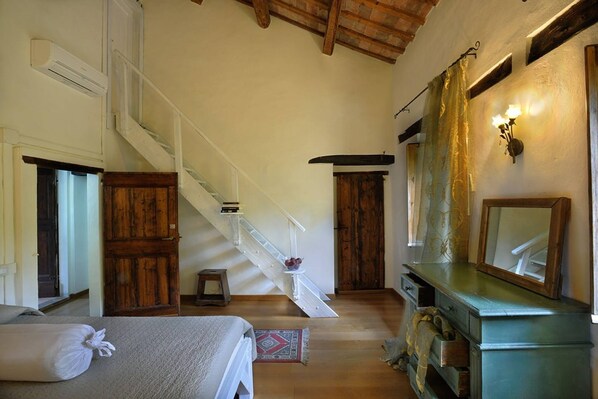 A bedroom with a bed, a dresser, a mirror, and a staircase leading to another room.