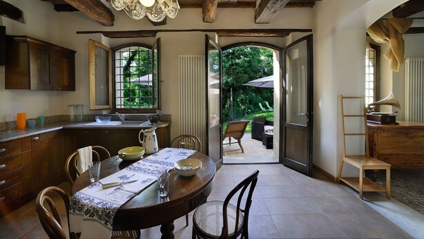 A dining area with a wooden table, chairs, and a view of the garden through open doors. - Luce tra i Faggi 8 in Montemaggiore al Metauro (Colli al Metauro)