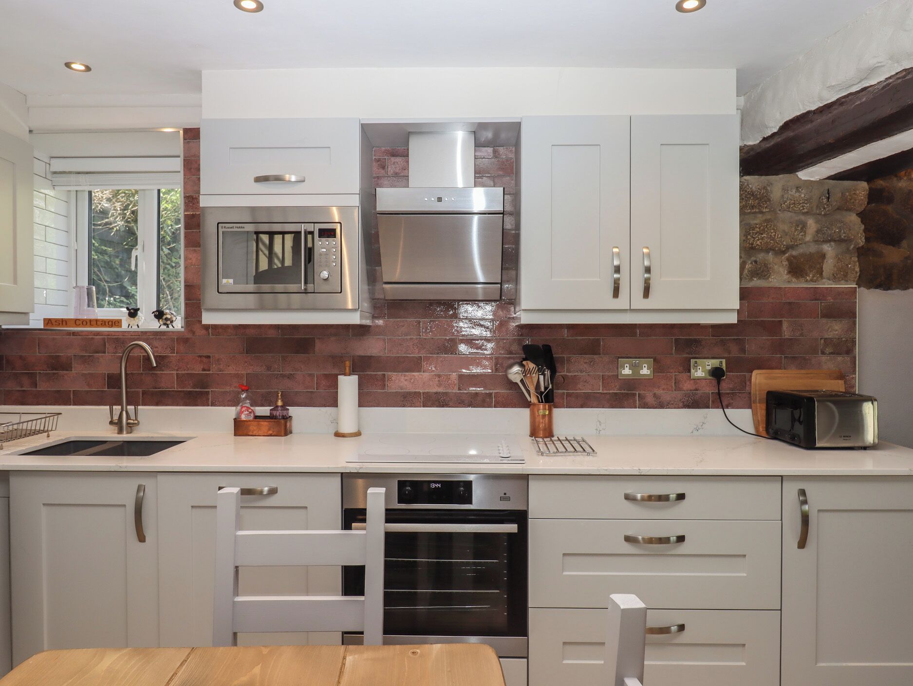 A modern kitchen with white cabinets, a stainless steel microwave, and a built-in oven.