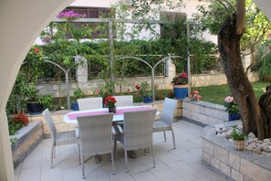An outdoor patio with a table and chairs, surrounded by potted plants and a stone wall.