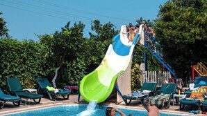 A swimming pool with a water slide and lounge chairs around the pool. - MARİN HOTEL (Kemer)