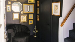 A hallway with a staircase, a black wall with framed pictures, and a black chair. - The Overlook on Chocolate (Hershey)