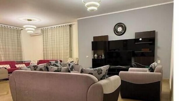 Un salon moderne avec un canapé gris, un téléviseur à écran plat et une horloge murale décorative.