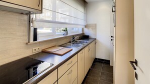 A modern kitchen with a built-in oven, a sink, and a window above the counter. - Apartment by the Seawall in Belgium (Knokke-Heist)
