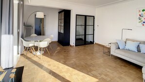 A spacious living area with a dining table and chairs, a sofa, and a cabinet. - Apartment by the Seawall in Belgium (Knokke-Heist)