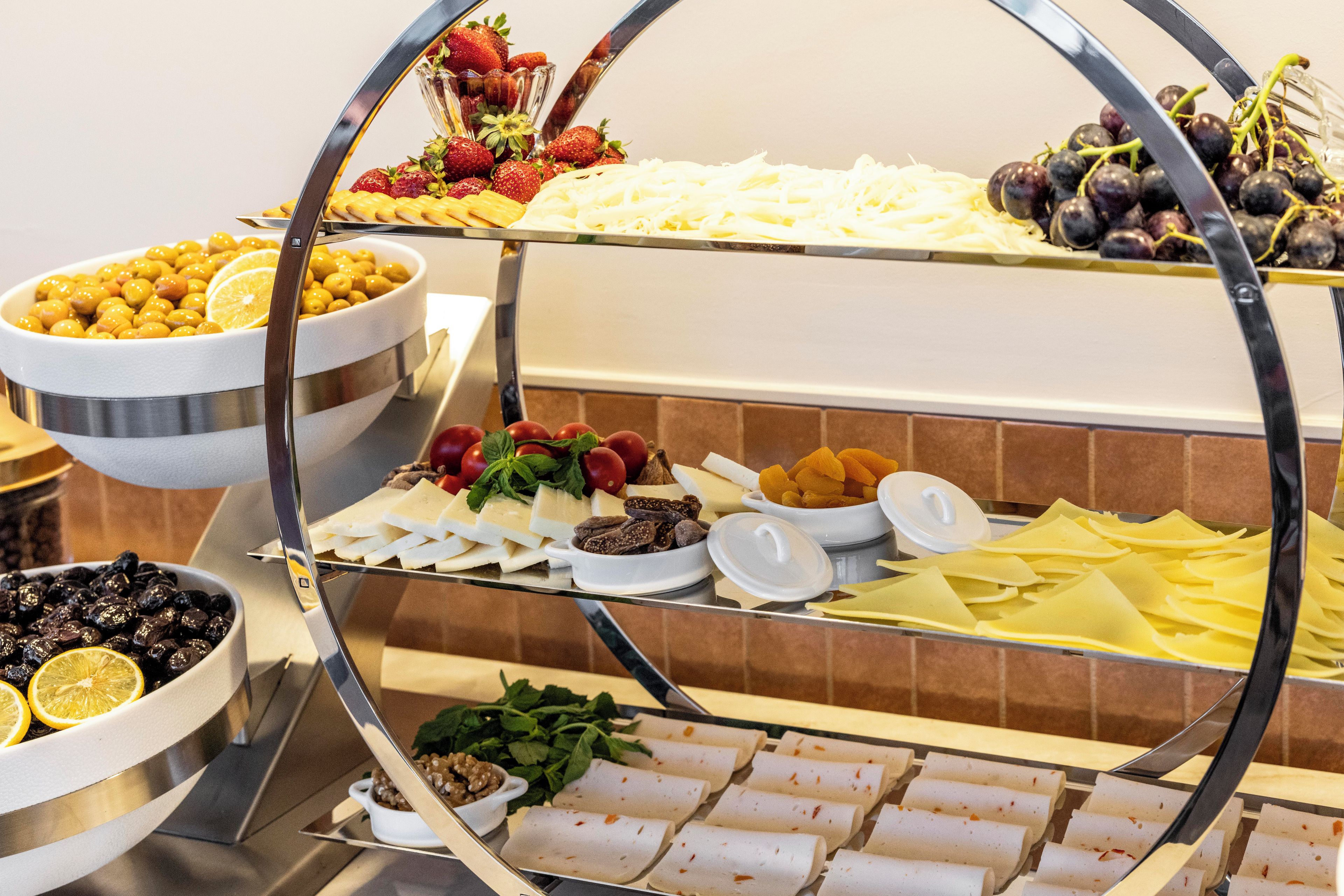 Een buffet met diverse gerechten, waaronder fruit, kazen en gebak.