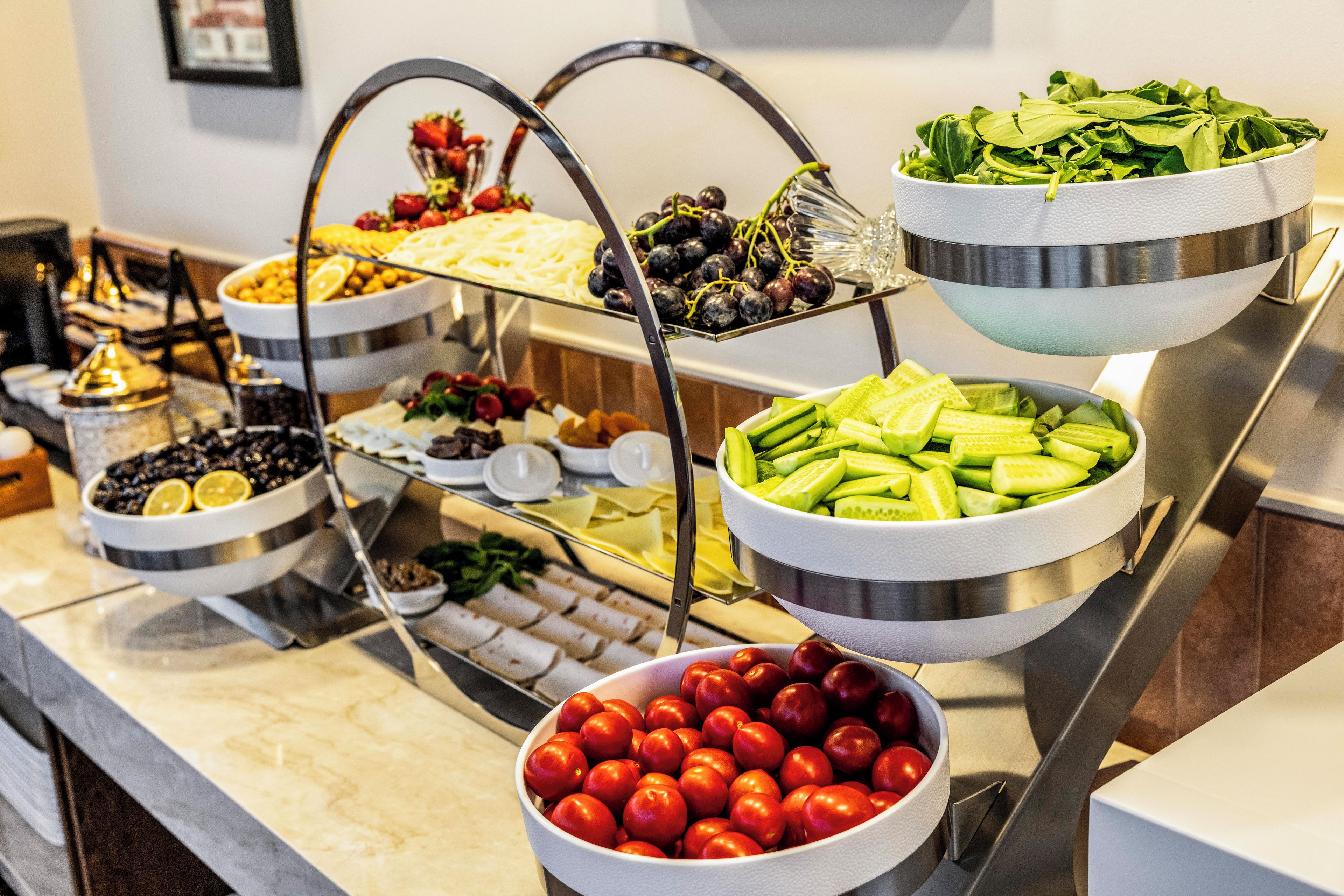 A buffet with various food items including fruits, vegetables, and cheeses.