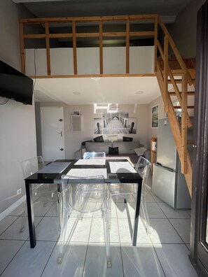Une cuisine moderne avec un coin repas, un escalier et une chambre à coucher située en mezzanine.
