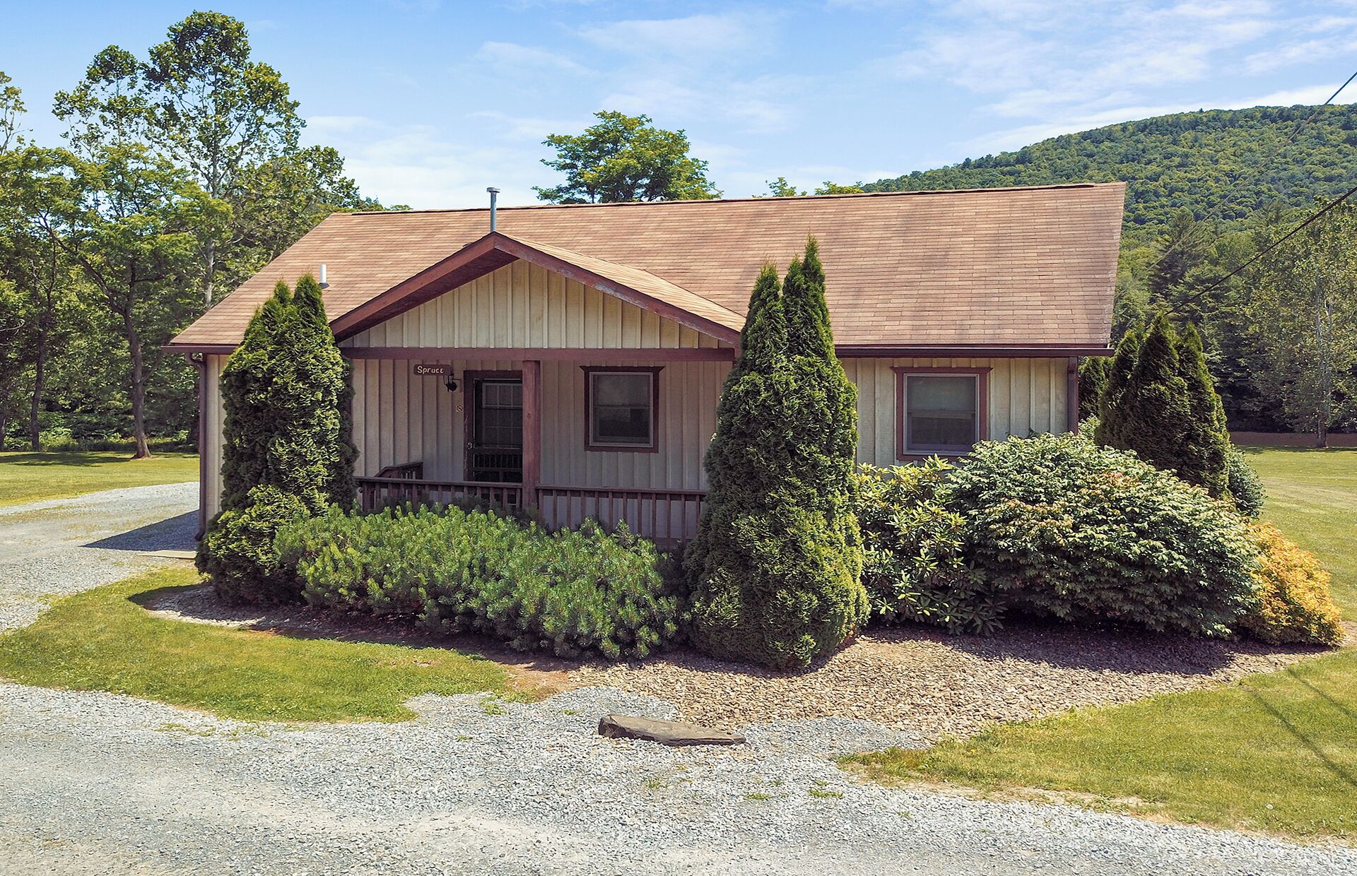A single-story house with a pitched roof, a front porch, and a gravel driveway.