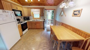 Une cuisine avec des meubles de rangement en bois, un réfrigérateur blanc, une cuisinière et une table à manger avec des chaises.