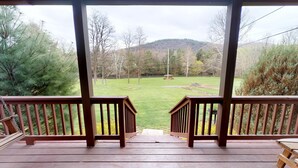 Une terrasse en bois offrant une vue sur une pelouse et une colline au loin.
