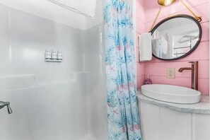 A bathroom with a shower, a sink, and a mirror. - Matlacha Tiny Village - Flamingo (Matlacha)
