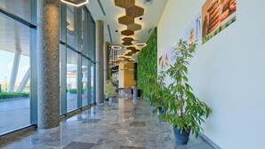 A modern lobby with a glass wall, a green wall with plants, and a polished marble floor. - Modern Furnished Apartments in Istanbul Basaksehir By Iradah Gayrimenkul (Istanbul)