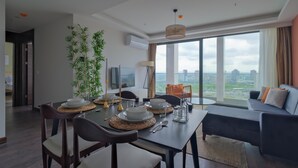 A modern living room with a dining area, large windows, and a city view. - Modern Furnished Apartments in Istanbul Basaksehir By Iradah Gayrimenkul (Istanbul)