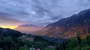 A mountainous landscape with a winding road, dense forest, and a small building. - Agathi Hotel  (Central Tzoumerka)