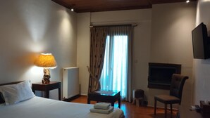 A hotel room with a bed, a desk, a chair, a TV, and a window with curtains. - Agathi Hotel  (Central Tzoumerka)