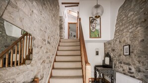 A staircase with stone walls, wooden railings, and a radiator. - Coach House (Llandysul)