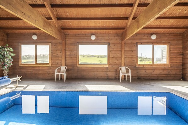 A wooden cabin with a pool, large windows, and a view of the countryside. - Cove Cottage (Llandysul)