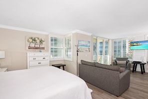 Enjoy a serene ocean view from the comfort of this stylish room, featuring a large bed, sofa, and table with a lamp.