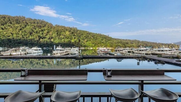 A marina with boats docked, a clear sky, and a forested hill in the background. - Shui Yang Lakeview House with Elevator (Nantou)