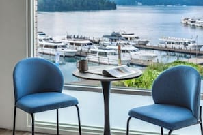 A room with a view of a marina, two blue chairs, a table with a cup and a menu. - Shui Yang Lakeview House with Elevator (Nantou)