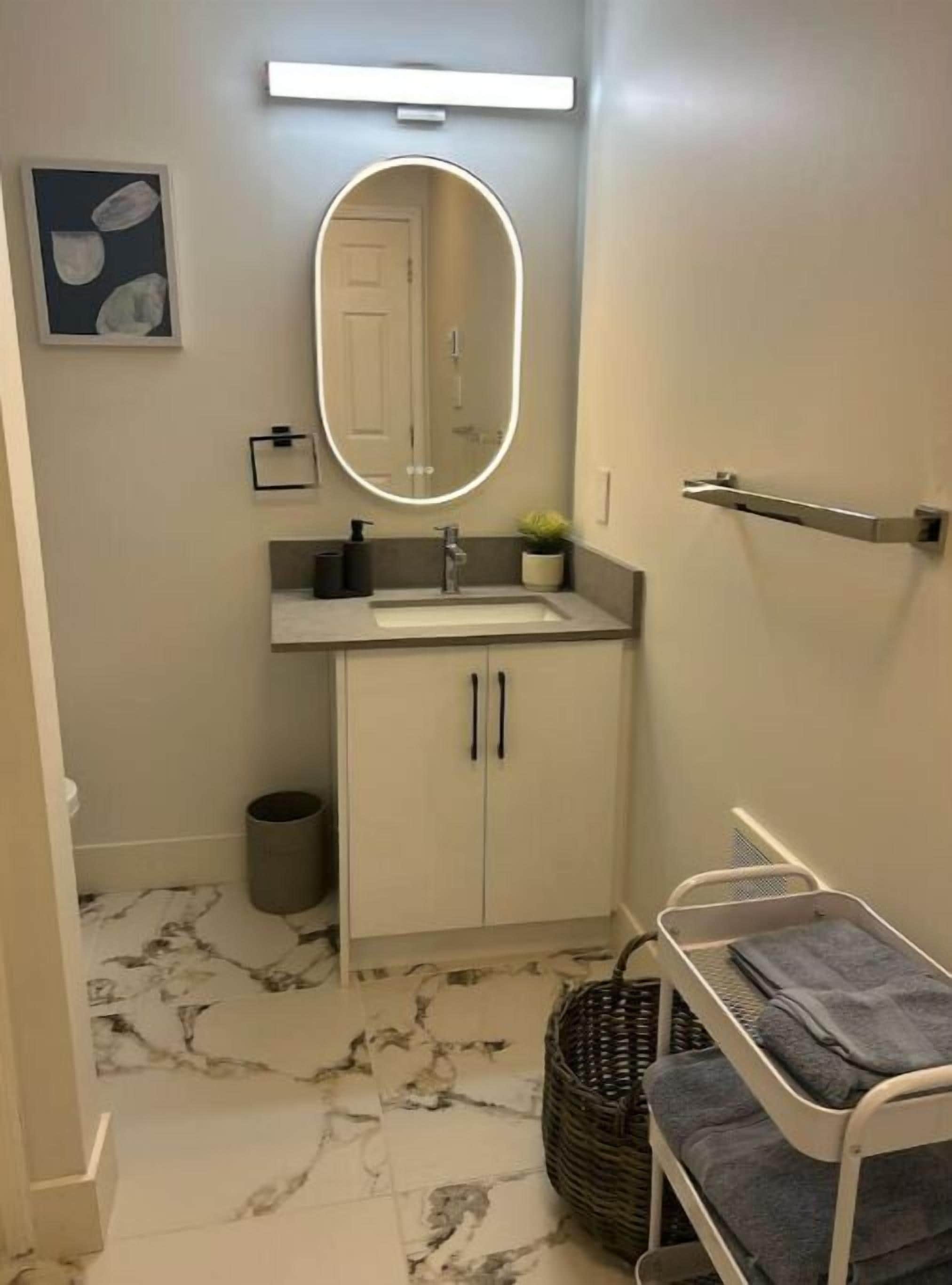 Ein Badezimmer mit Marmorboden, Waschbecken mit Spiegel, Schrank und einer kleinen Ablage.