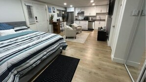 Una habitación compacta y moderna con cama, una pequeña zona de estar y kitchenette.