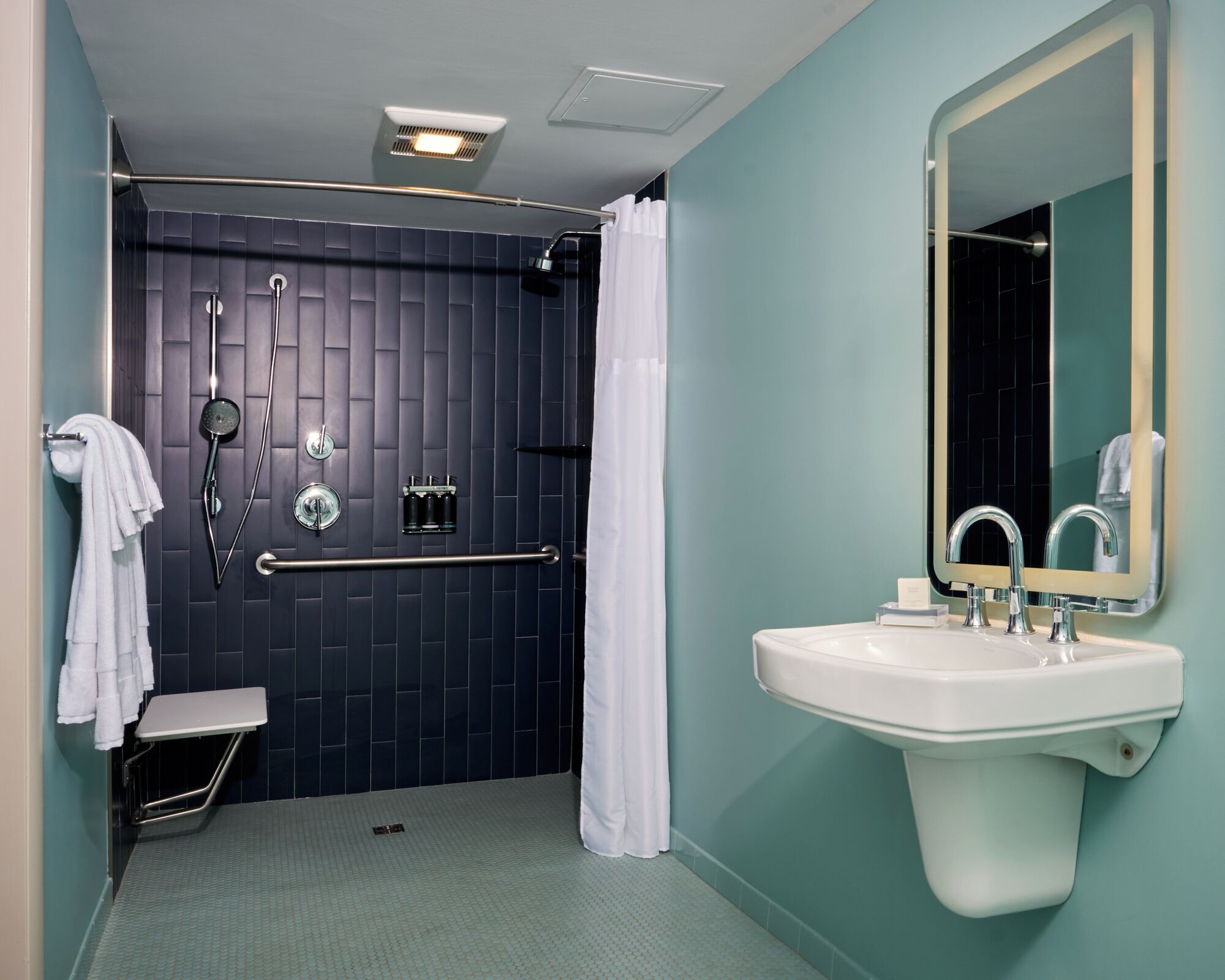 A bathroom with a shower, a sink, and a mirror.