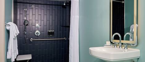 A bathroom with a shower, a sink, and a mirror.
