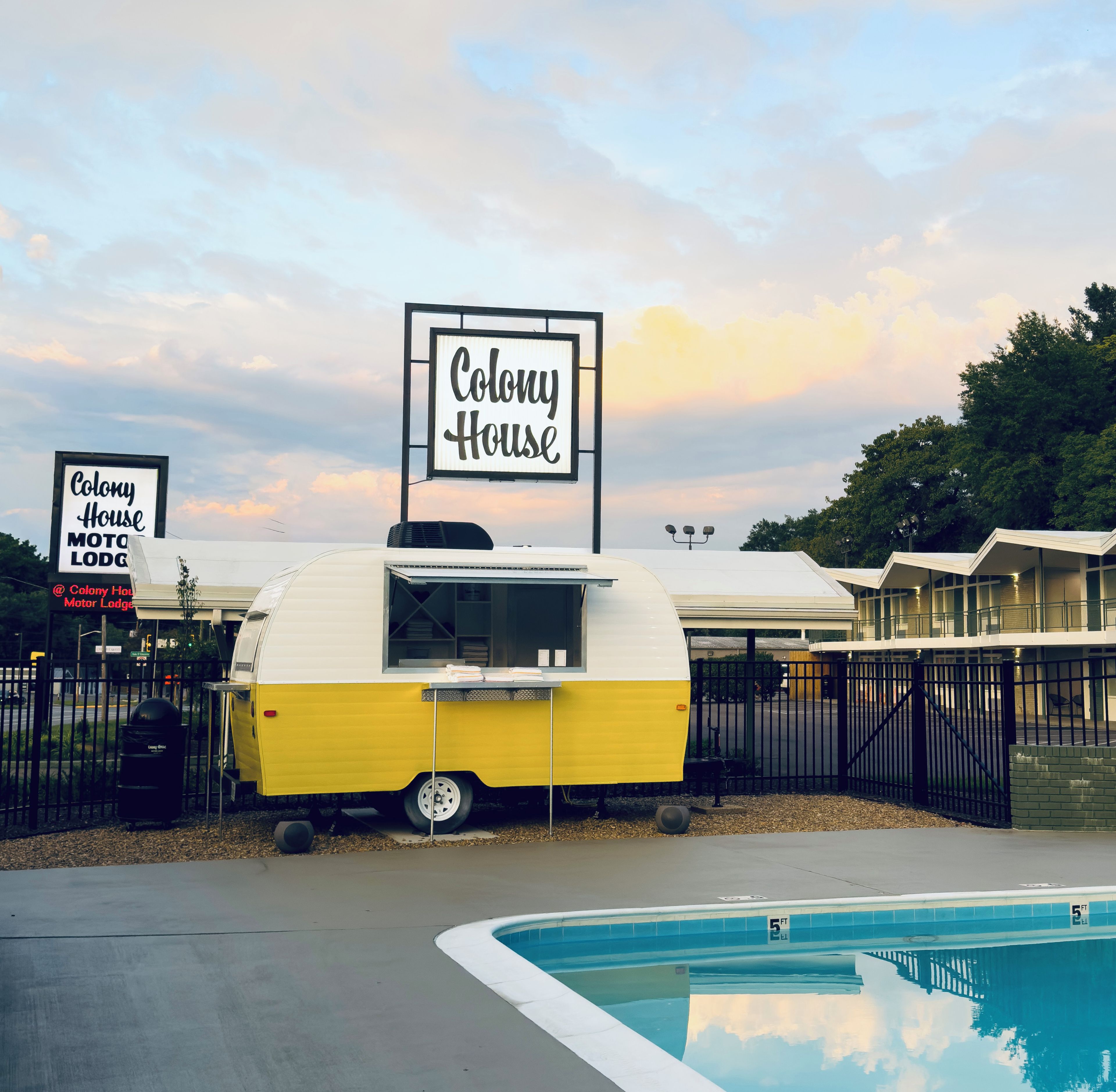 Ein Motel mit einem Schild, auf dem 'Colony House' steht, und einem gelben Wohnwagen.