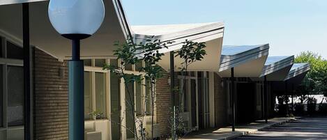 A modern building with a covered outdoor area, a street lamp, and a parking lot.