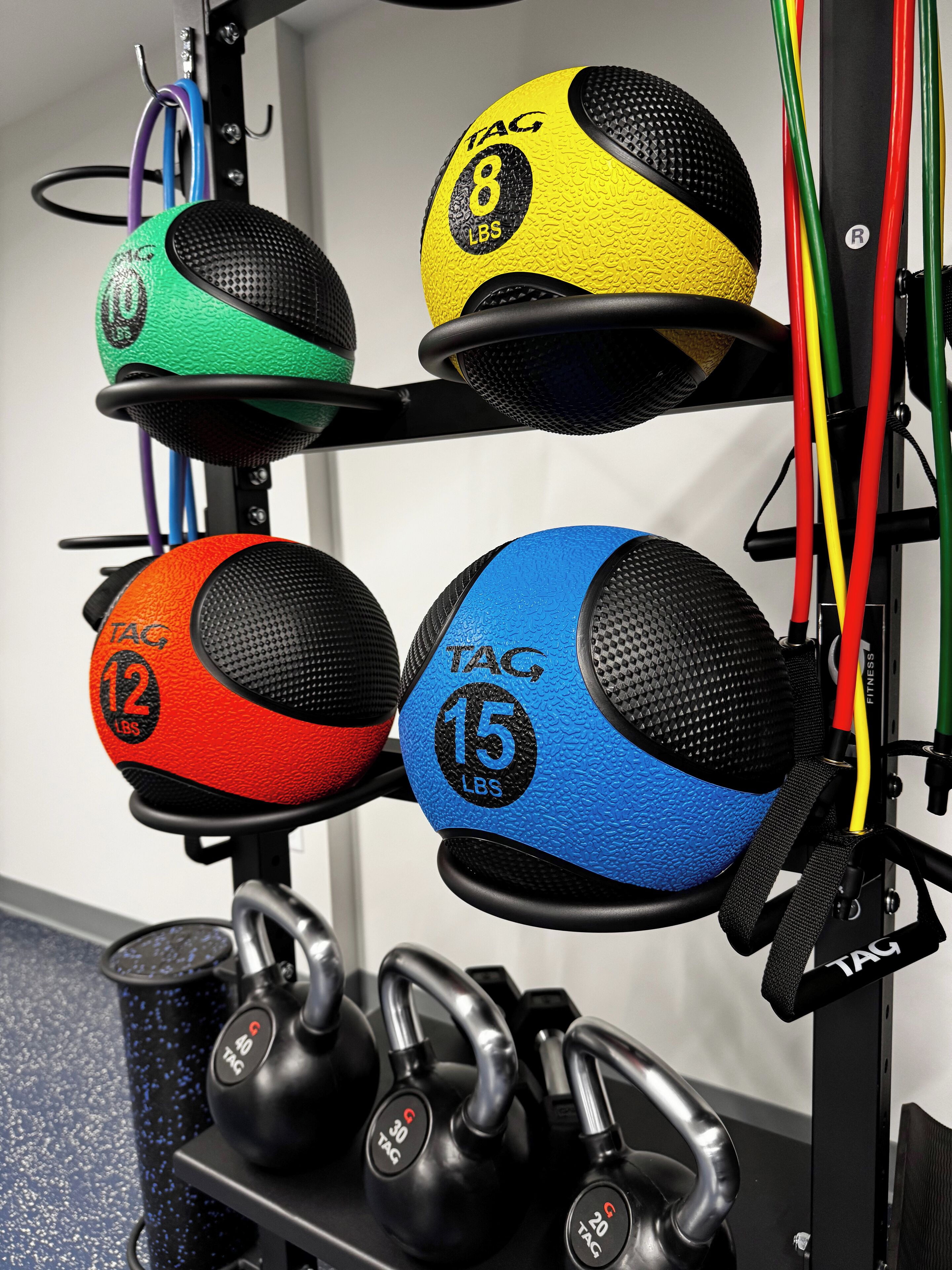 A rack with various exercise equipment including kettlebells, medicine balls, and resistance bands.