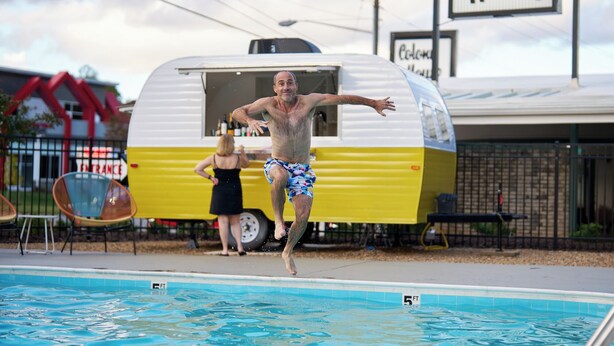 A swimming pool with a sign reading 'Colony House' in the background. - Colony House Motor Lodge (Roanoke)