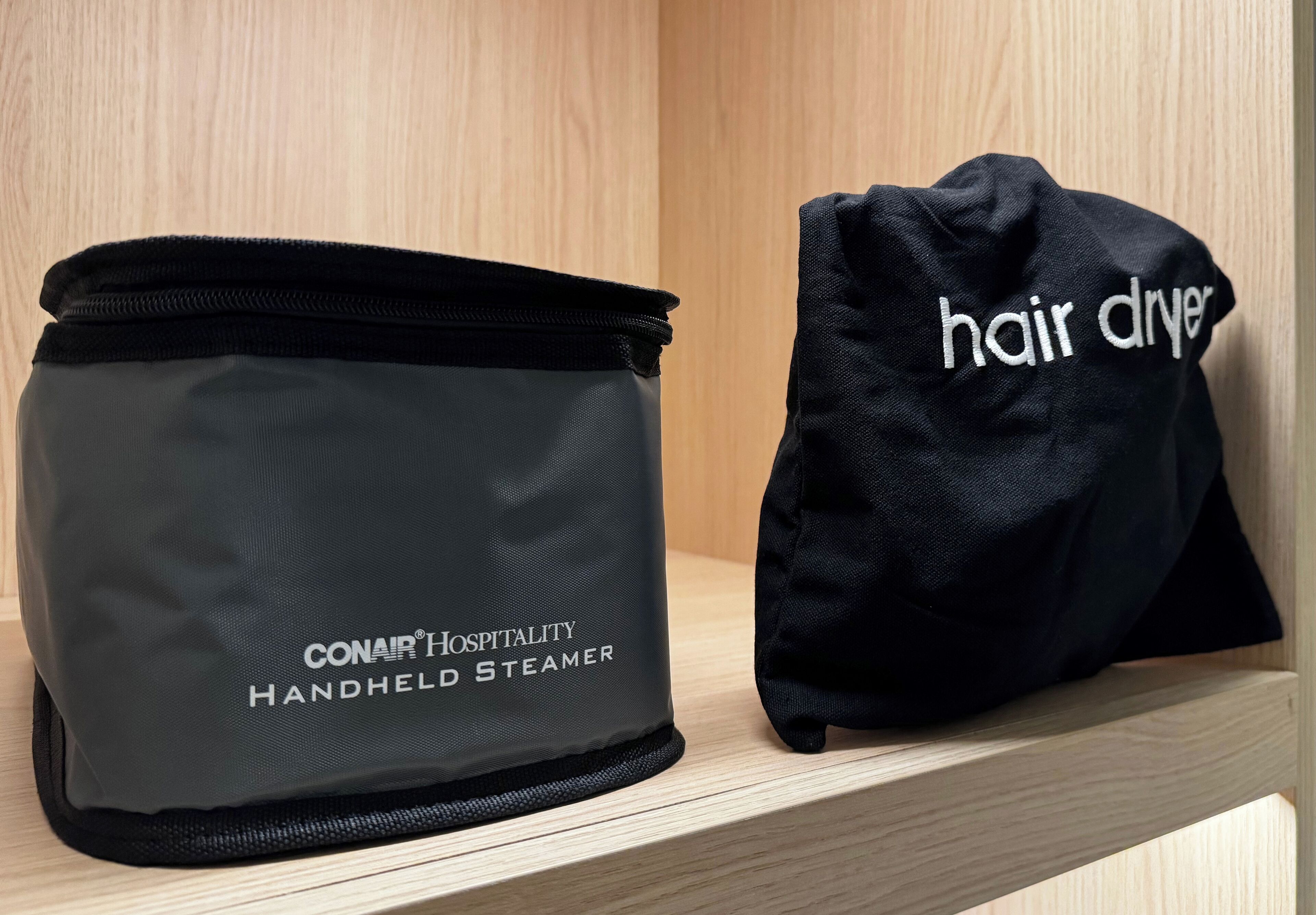 Ein CONAIR Hospitality Handdampfgerät und eine schwarze Tasche mit dem Aufdruck "hair dryer".