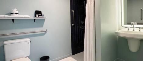 A bathroom with a toilet, a sink, a shower with a curtain, and a mirror with a light.